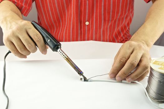 Man repair a white usb cable by black soldering with lead.