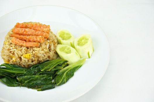 Shrimp fried rice vegetarian with kale, carrots and cucumber on a plate with white background.