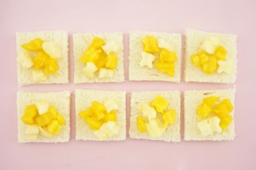 Mango and apple sliced put on small bread in row on pink tray.
