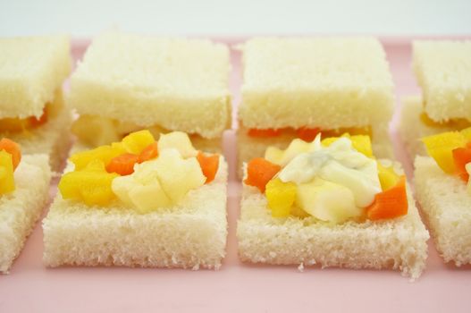 Carrot, Mango, apple and cucumber sliced put on small bread with cream salad in row for make sandwich on pink tray.