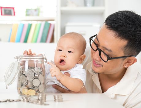 Asian family lifestyle at home. Father and child saving coins to money jar, financial planning concept.