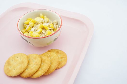 Mix corn, oats and sweetened condensed milk placed on pink tray with white background.