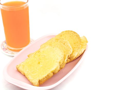 Bread baked with butter and sugar placed in a pink tray with orange juice on white background.