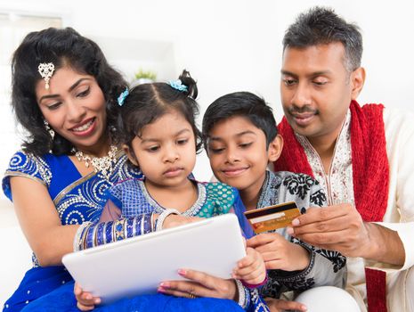 Indian Asian family using digital tablet pc computer online shopping with credit card at home. India family living lifestyle. 