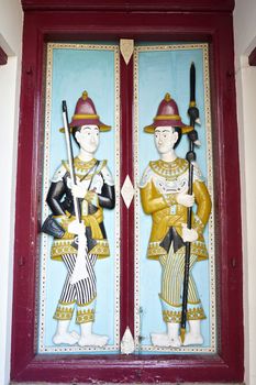 Soldier hold gun and spear on door of the building, which is located on the Temple of the Emerald Buddha.