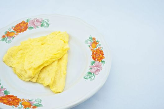 Omelette made a triangle placed on the plate with white background.