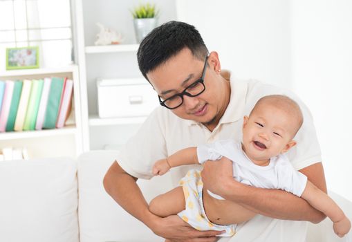 Asian family lifestyle at home. Father flying baby boy, having fun time together.