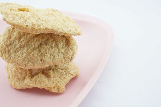 Vegan Protein Dry stacked on pink tray with white background.