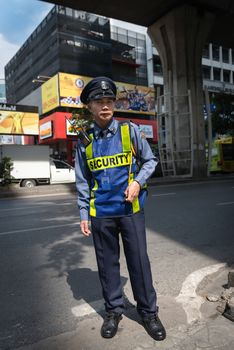 BANGKOK, THAILAND - 21 NOV 2013: Unidentified security man in uniform stands on street and controls passage to office building.