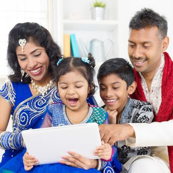 Indian family using digital computer tablet at home. Asian family living lifestyle.