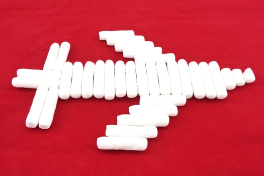 Foam shape as cylinder  placed like airplane on red background.