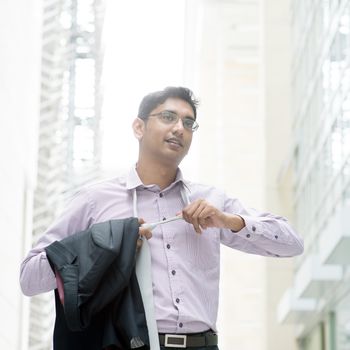 Portrait of a Indian businessman taking off his tie
 after working hours, walking at modern building.
