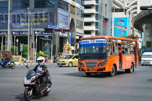 BANGKOK, THAILAND - 21 NOV 2013: Public transport bus and motorbike pass crossroads street with modern buildings on background