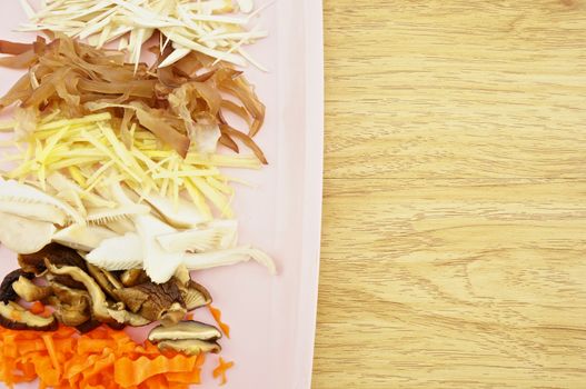 Carrot, lentinula, oyster mushroom, ginger, auricularia slice put on pink tray with wood background.