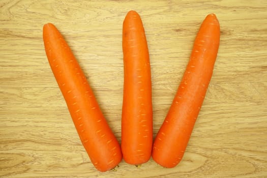 Carrot is orange vegetable with carotene put as fork on wood background.