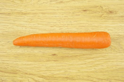 Carrot is orange vegetable with carotene put on wood background.