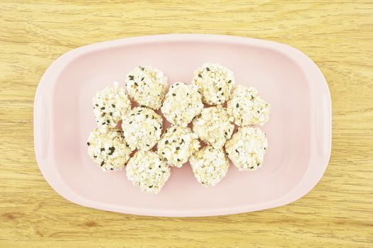 Popped rice mix black sesame place on a pink tray with wood background.