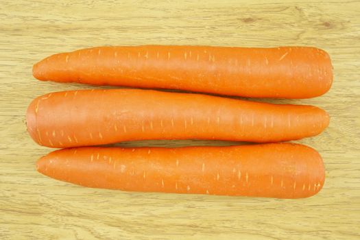 Carrot is orange vegetable with carotene put on wood background.