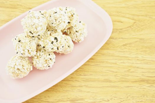 Popped rice mix black sesame  place on a pink tray with wood background.