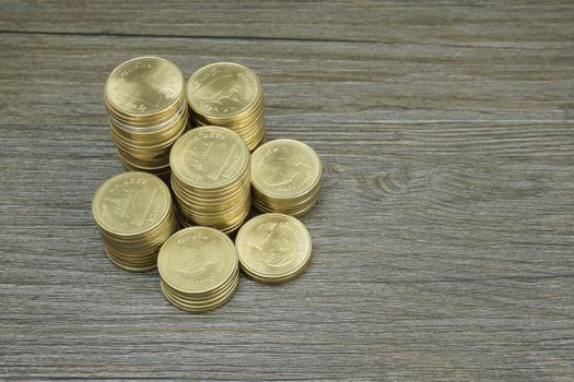 Gold coin of Thai baht pile on black wood background.