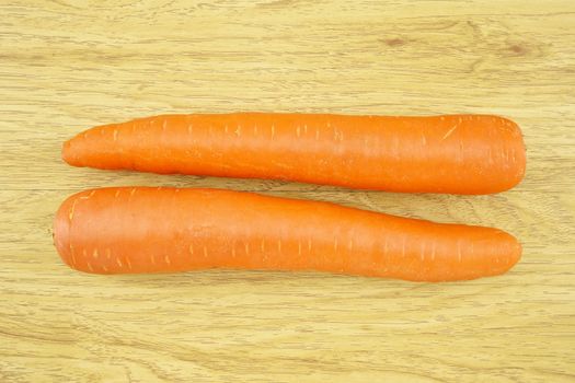 Carrot is orange vegetable with carotene put on wood background.