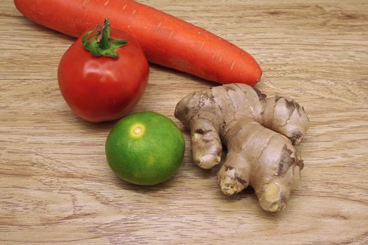 Tomato, lemon, ginger and carrot is colorful vegetable put on wood background.