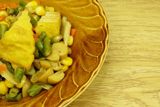 Tofu fried carrot, champignon mushroom, corn, vigna unguiculata sesquipedalis on dish with wood background.