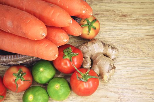 Tomato, lemon, ginger and carrot in basket is colorful vegetable put on wood background.