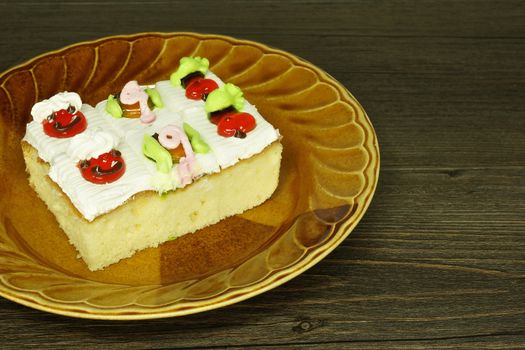 Slice cake topping with jam and cream as fruit and animal  on wood background.