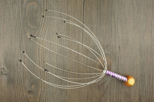 Head massage tool made of wire place on wood background.