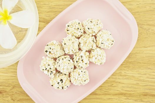 Popped rice mix black sesame  place on a pink tray with wood background.