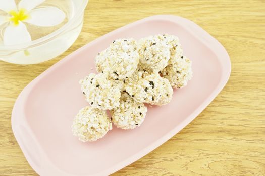 Popped rice mix black sesame  place on a pink tray with wood background.