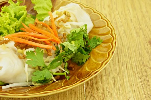 Close up wide rice noodle roll place on left with wood background.