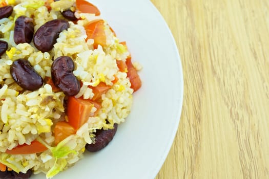 Close up fried rice with red bean, tomato and lettuce is vegetarian food on wood background.