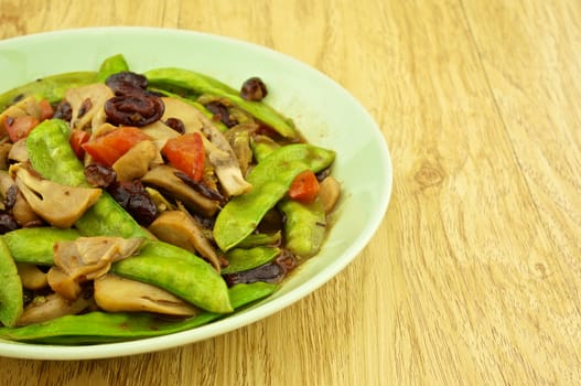 Close up green pea fried with red bean, tomato and mushroom on wood background.