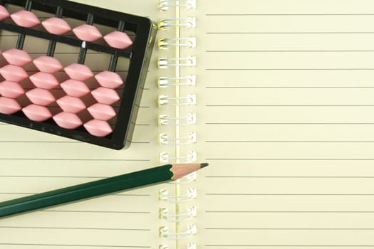 Pink and black abacus retro japan calculator put on notebook with pencil.