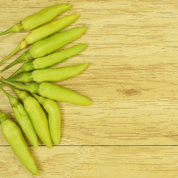 Green chili on left taste hot and spicy with wood background.