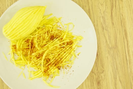 Mango slice with cayenne pepper and sugar on wood background.