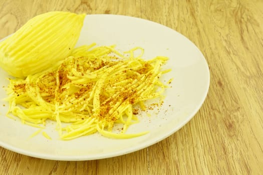 Mango slice with cayenne pepper on wood background.