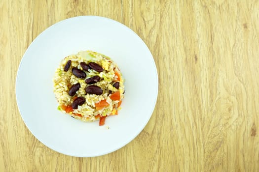 Fried rice with red bean, tomato and lettuce is vegetarian food on wood background.