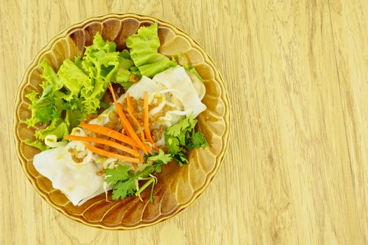 Wide rice noodle roll place on left with wood background.