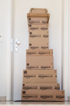 OSTFILDERN-SCHARNHAUSEN, GERMANY - MAY 18, 2014: A large stack of parcels by Amazon.com in different sizes is awaiting its customer in front of an entrance door of a flat on May, 18, 2014 in Ostfildern-Scharnhausen near Stuttgart, Germany. This conceptual photo can serve different purposes: It might demonstrate the domination of Amazon.com in the area of online shopping or the trend in general to shop online for all the different items you need in your personal life.