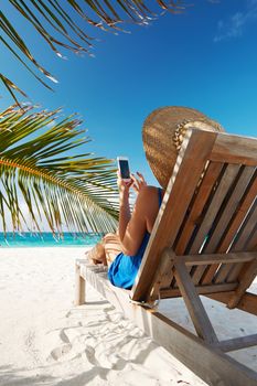 Young woman in hat with mobile phone at the beach