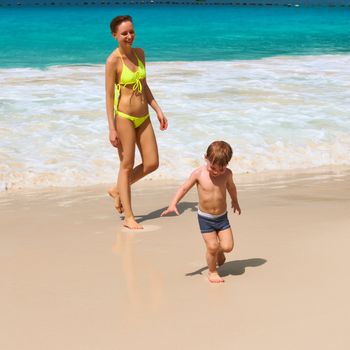 Two year old baby boy and his mother playing on beach at Seychelles