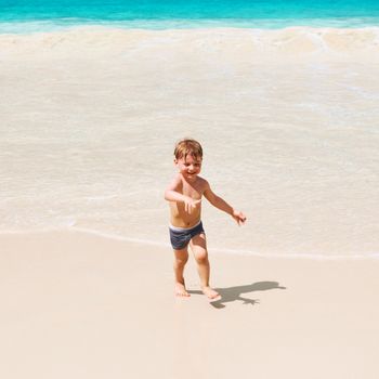 Two year old baby boy playing on beach at Seychelles