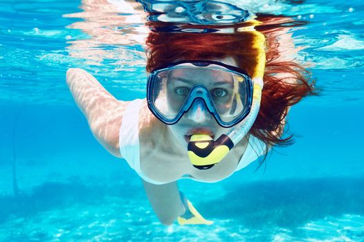 Woman with mask snorkeling in clear water 