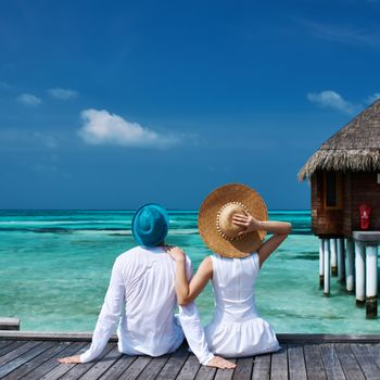 Couple on a tropical beach jetty at Maldives