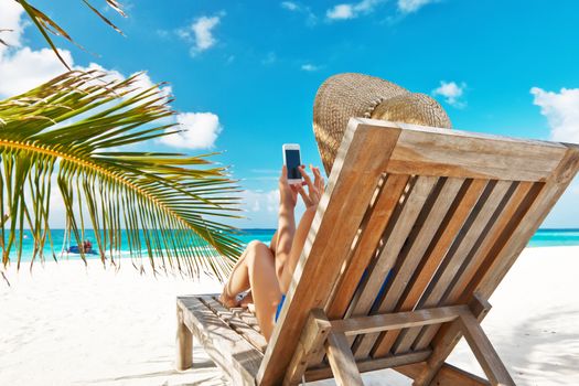 Young woman in hat with mobile phone at the beach