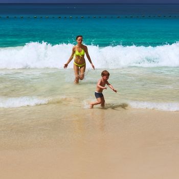 Two year old baby boy and his mother playing on beach at Seychelles