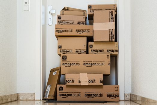 OSTFILDERN-SCHARNHAUSEN, GERMANY - MAY 18, 2014: A large stack of parcels by Amazon.com in different sizes is awaiting its customer in front of an entrance door of a flat on May, 18, 2014 in Ostfildern-Scharnhausen near Stuttgart, Germany. This conceptual photo can serve different purposes: It might demonstrate the domination of Amazon.com in the area of online shopping or the trend in general to shop online for all the different items you need in your personal life.
